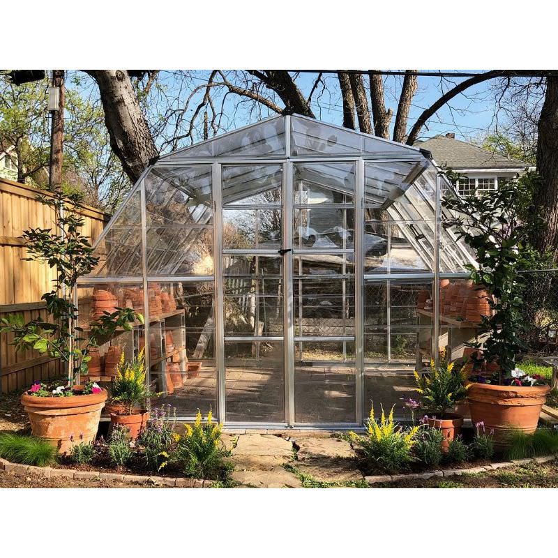 palram americana 12x12 greenhouse surrounded by potted plants